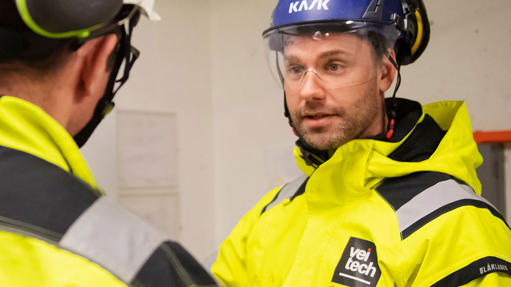 Två medarbetare på Veitech pratar med varandra inomhus.